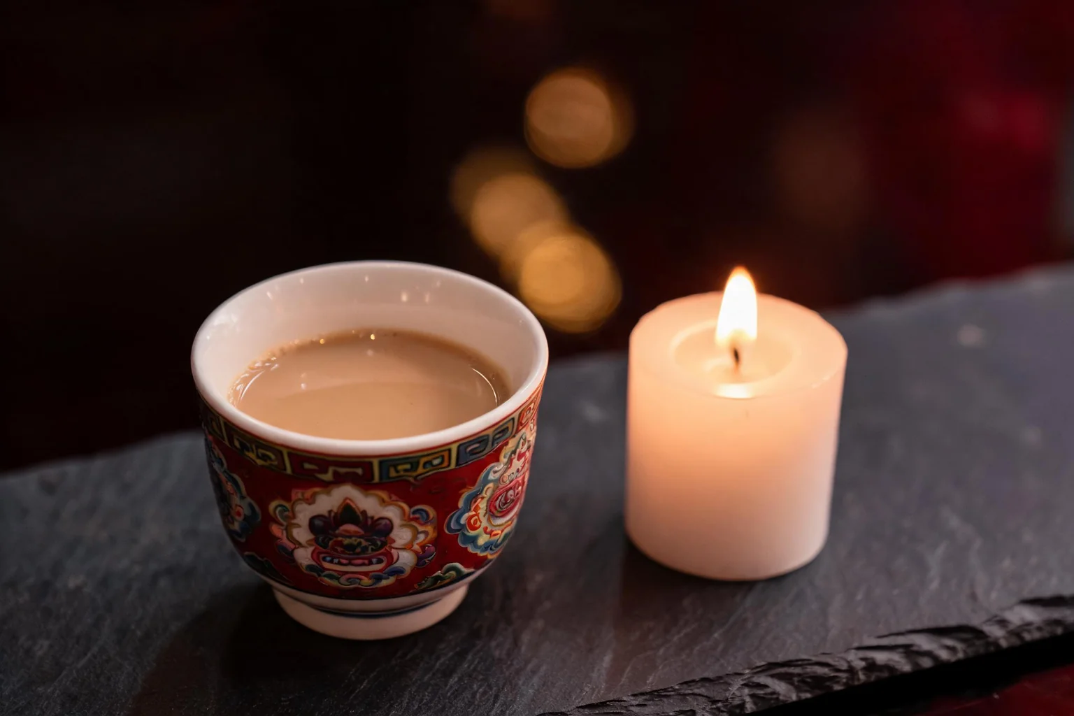 A table set for the evening, a lit candle and a traditional cup